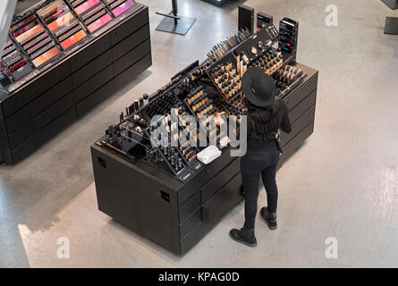 An unidentified young lady tidies the MAC cosmetics counter at Macy's Herald Square in Manhattan, New York City, Stock Photo