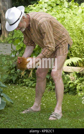 Model release, Pensionist mit Henne in der Wiese - pensioner with chicken in meadow Stock Photo