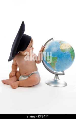 Model release, Kleinkind mit Doktorhut sitzt neben Globus - little child with doctoral cap next to a globe Stock Photo