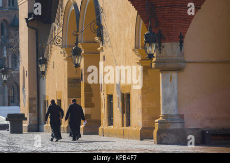 Catholic priests walking, rear view of two priests walking through the Market Square in Krakow, Poland, on a summer morning. Stock Photo