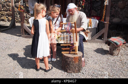 Сhildren are interested in the work of a weaver on the Trakai Crafts festival Stock Photo