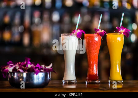 Composition with 3 yellow, white, red cocktails and orchid flowers on the blurred background Stock Photo