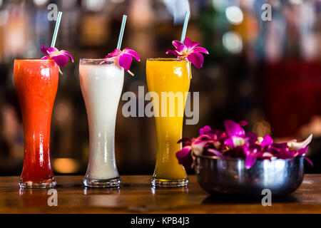 Composition with 3 yellow, white, red cocktails and orchid flowers on the blurred background Stock Photo