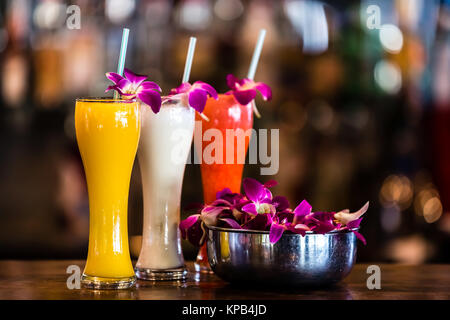 Composition with 3 yellow, white, red cocktails and orchid flowers on the blurred background Stock Photo