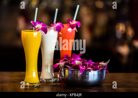 Composition with 3 yellow, white, red cocktails and orchid flowers on the blurred background Stock Photo