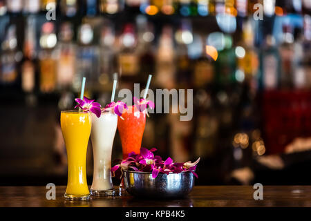 Composition with 3 yellow, white, red cocktails and orchid flowers on the blurred background Stock Photo