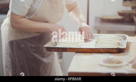 Cook puts pies on the tray for baking Stock Photo