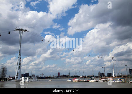 London cable car going across the Thames river with cloudy sky background and boats in the foreground, taken from North Greenwich side of the river Stock Photo