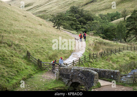 People walking in the countryside near the stone bridge over the River Noe, Vale of Edale, Derbyshire, Peak District National Park, England, UK Stock Photo