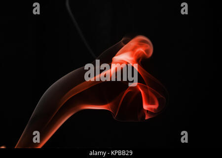 A whisp of red smoke against the black background Stock Photo