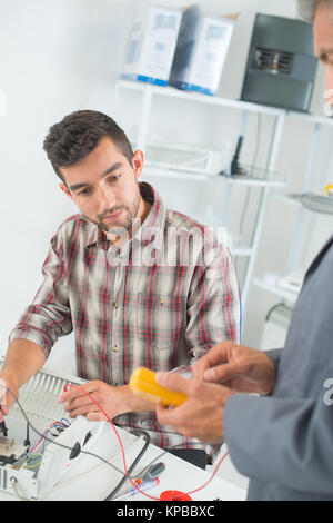 man repairing electronic device using multimeter Stock Photo