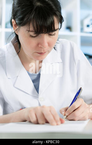 Scientist or a medic in a white coat making notes Stock Photo