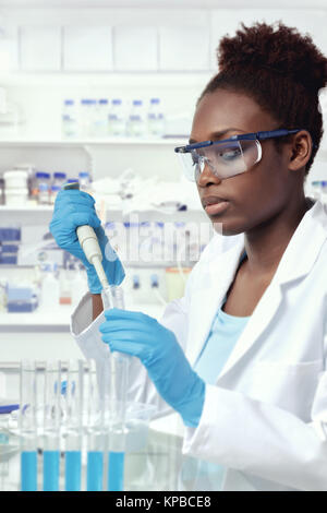 African-american scientist or graduate student in lab coat and protective wear works in modern laboratory Stock Photo