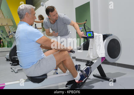 senior man in gym using a rowing machine Stock Photo