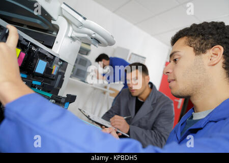 doubting man fixing copier in the office Stock Photo