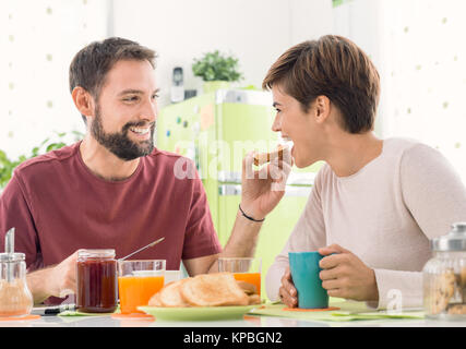 Young loving couple having breakfast at home in the kitchen, the man is feeding her wife, love and relationships concept Stock Photo