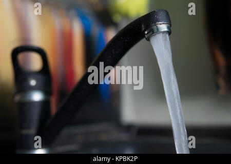 water leakage from the tap. Granite style. jet clean drinking water. For drinking water from the black tap in the sink granite in the kitchen. Stock Photo