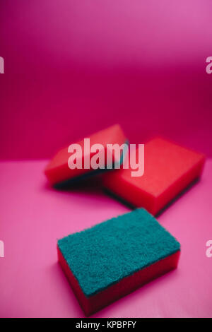 Cleanup in a kitchen. A bright abstract composition with scrub dishwashing sponges on a bright pink background. Close up Stock Photo