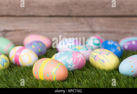Colorful Easter eggs on grass against a wood background Stock Photo