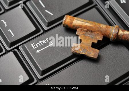 Macro shot of antique rusty key on black Enter computer key. Stock Photo