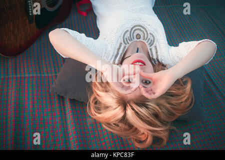 Smiling blonde girl looking through her hands in the form of hea Stock Photo