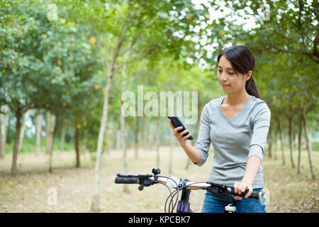 Woman checking the GPS on mobile phone when cycling Stock Photo