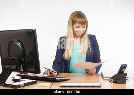 Secretary working in the office computer, look in the paper document Stock Photo