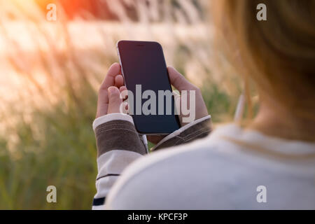 woman holding smartphone during sunset Stock Photo