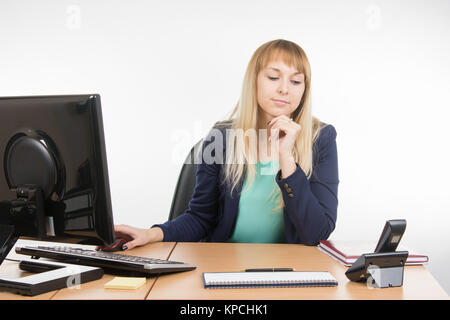 Secretary working at a computer looking at the phone rang Stock Photo