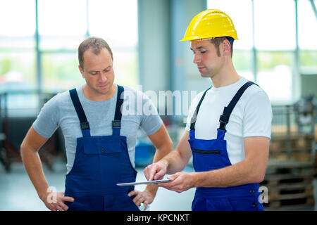 two young worker in factory using tablet pc Stock Photo