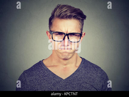 Young expressive man in black eyeglasses looking at camera with expression of total disbelief and frustration Stock Photo
