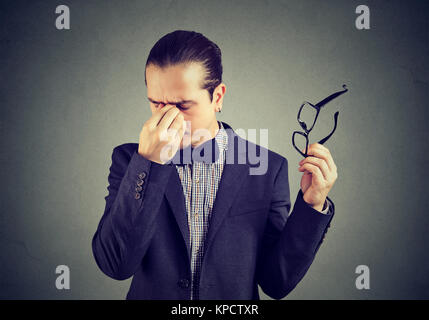 Elegant man taking off glasses and rubbing nose bridge looking tired. Stock Photo