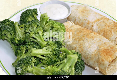 Two filled Tortilla wraps with a side of fresh broccoli and a container of creamy dressing for dipping Stock Photo