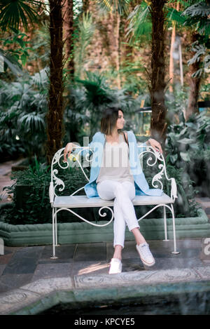 Woman in Dress Poses Near Flowers in Garden. Brunette Girl Sitting on a  Plaid in the Park on the Nature. Spending Time Stock Photo - Image of  natural, model: 210817596