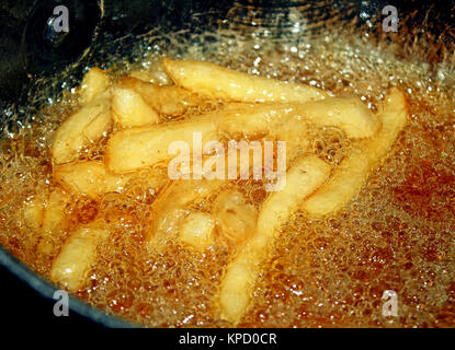 French fries cooking in oil filled deep fryer Stock Photo