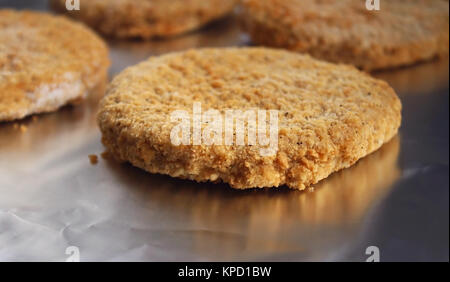 Frozen breaded chicken burger patty of foil - ready for cooking Stock Photo
