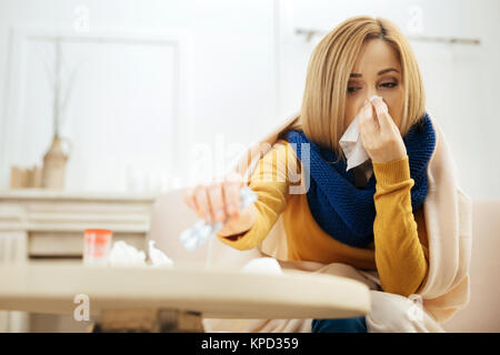 Sick woman taking temperature and having runny nose Stock Photo