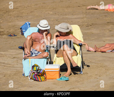 Mature couple reading on beach Stock Photo