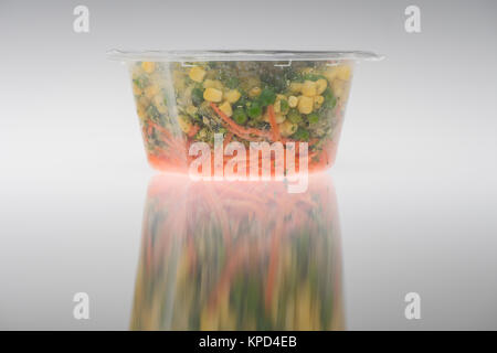 Ready made vegetables in plastic pot ready for eating on a white background, peas, sweet corn and carrots. Stock Photo