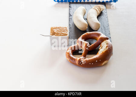 a few white sausages and pretzels are on a slate plate,sweet mustard and a napkin off the mark. the taste of the snack! Stock Photo