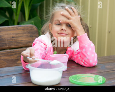 Six-year girl pours sugar in tea spoon a small breakfast on the veranda Stock Photo