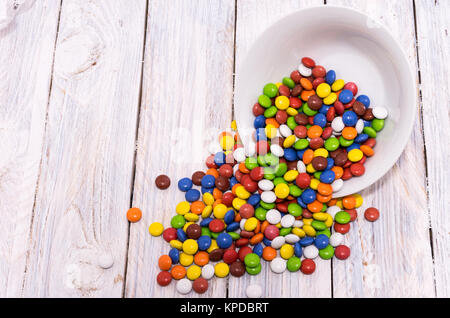 Inverted plate. Spilled candy on the table. White wooden table. Stock Photo