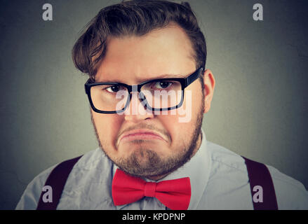 Headshot of chubby man in red bowtie and glasses looking at camera with expression of displeasure. Stock Photo