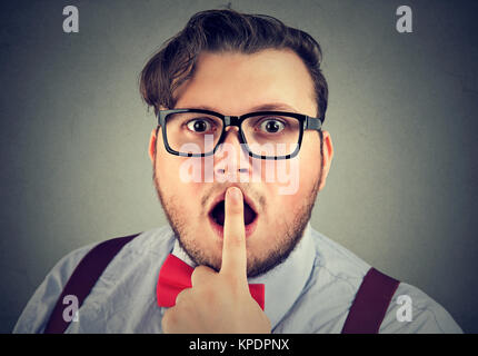 Portrait of bearded man in glasses touching lips while looking impressed with new genius idea. Stock Photo