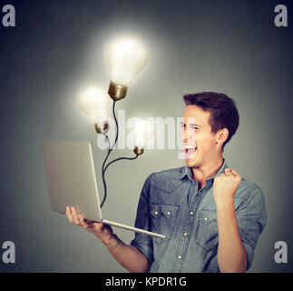 Young man holding laptop and celebrating success of great ideas. Stock Photo