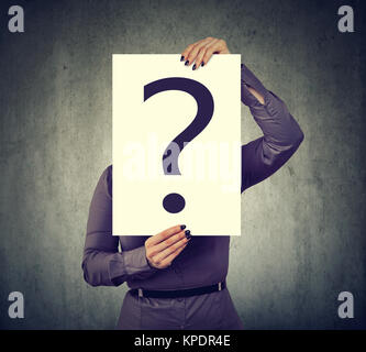 Unrecognizable woman holding paper with question mark in front of face posing on gray. Stock Photo