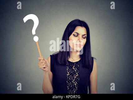 Young girl in black holding question mark looking confused about new information. Stock Photo