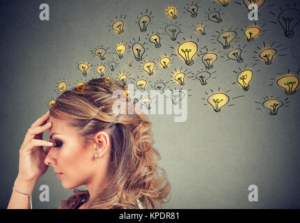 Young woman thinking with concentrated having many ideas with backdrop of burning lightbulbs. Stock Photo