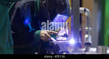 Industrial worker welding in metal factory. Stock Photo