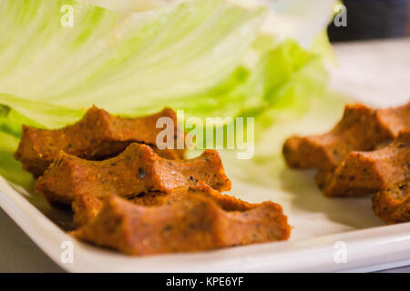cigkofte turkish meatball from bulgur with tomato, lemon and lettuce sides top view Stock Photo